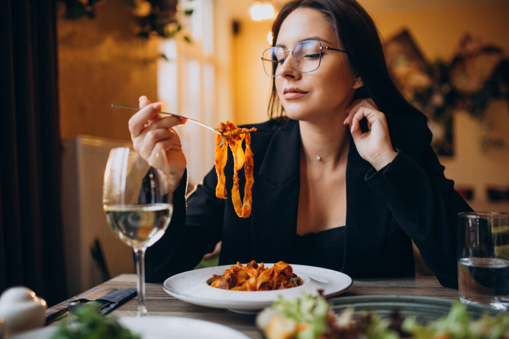 Young woman eating pasta in a cafe